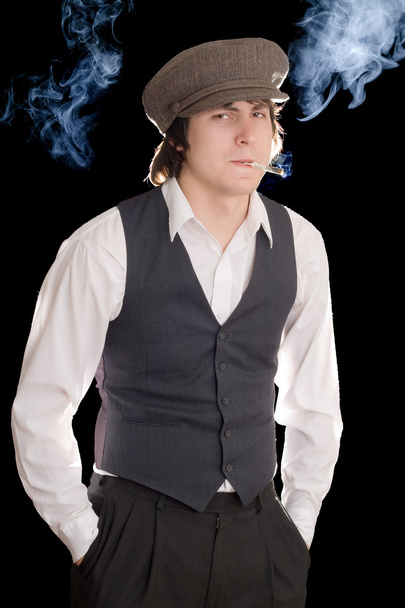 Молодой человек курит с осторожным взглядом. Изолированный на черном
 - Фото, изображение