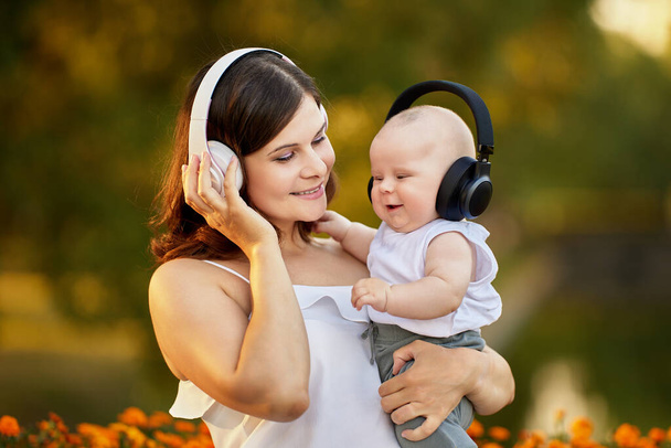 Mère et enfant heureux dans des écouteurs sans fil pendant la marche à l'extérieur. - Photo, image