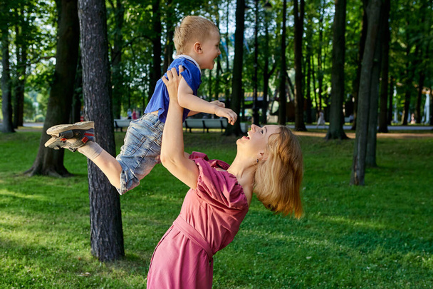 Happy woman holds little child in city garden. - Фото, зображення