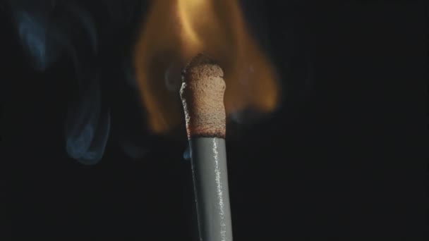 Extreme close-up shot van lange wedstrijd branden en uitstoten slipjes rook op zwarte achtergrond - Video