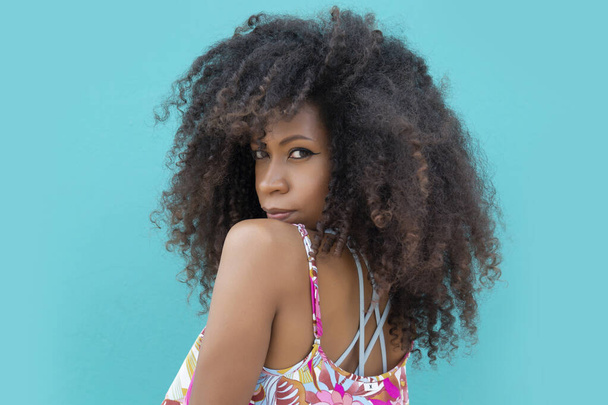 bella giovane donna afro posa civettuola su un acquamarina sfondo blu - Foto, immagini