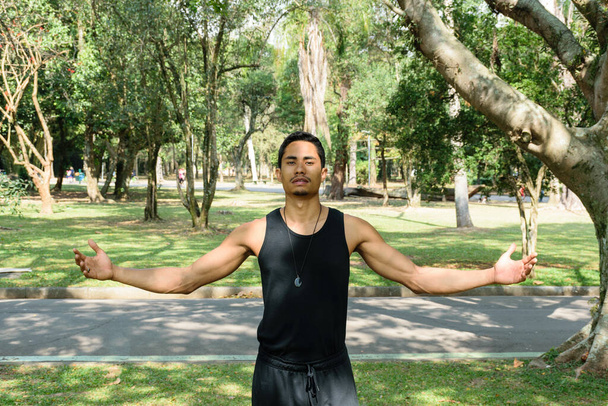 Junge Brasilianerin, Yogalehrerin, mit offenen Armen an einem sonnigen Tag in einem öffentlichen Park. - Foto, Bild