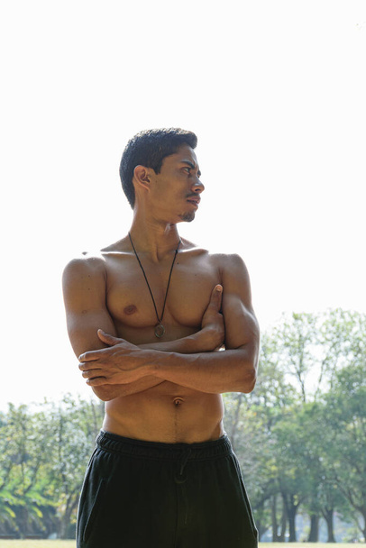 Młody Brazylijczyk bez koszuli, skrzyżowane ramiona, oświetlony od tyłu światłem słonecznym. - Zdjęcie, obraz