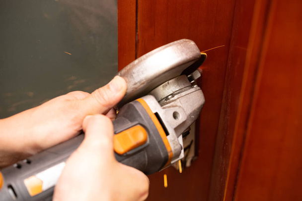 hombre cortando una cerradura de puerta por una amoladora - Foto, imagen