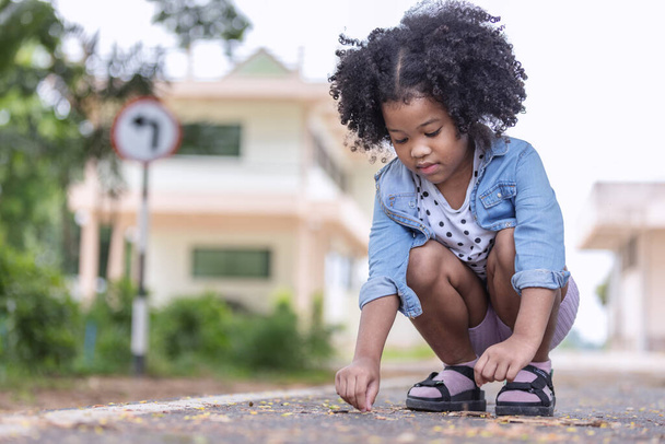 klein Afrikaans Amerikaans krullend haar meisje zitten alleen en denken iets .Childhood en geestelijke gezondheid. - Foto, afbeelding