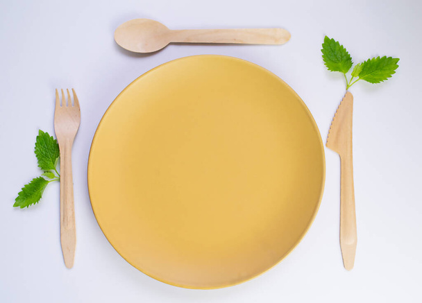 tuore minttu keltaisella lautasella, jossa on puiset ruokailuvälineet. Laadukas kuva - Valokuva, kuva