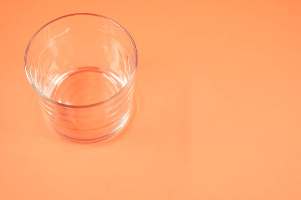 An empty drinking glass isolated on orange background with free space for text - Photo, image