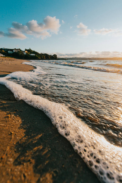 The foamy waves washing the sandy beach on a sunny day - Fotografie, Obrázek