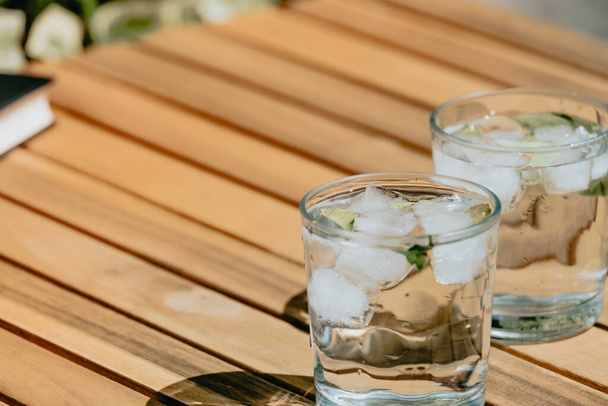Szklanka wody z lodem na drewnianym stole na zewnątrz - Zdjęcie, obraz