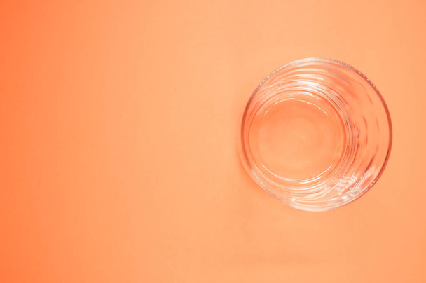 An empty drinking glass isolated on orange background with free space for text - Фото, изображение