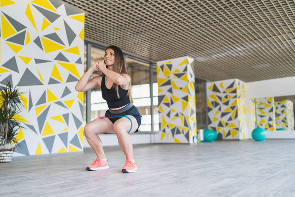 A shot of a sporty girl doing squats in the gym - Fotó, kép