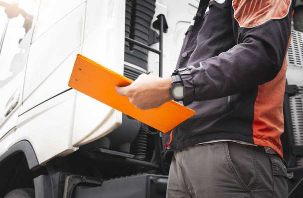 Auto Mechanic Driver Holding Clipboard is Checking Maintenance and Safety Program of Semi Truck. - Фото, изображение