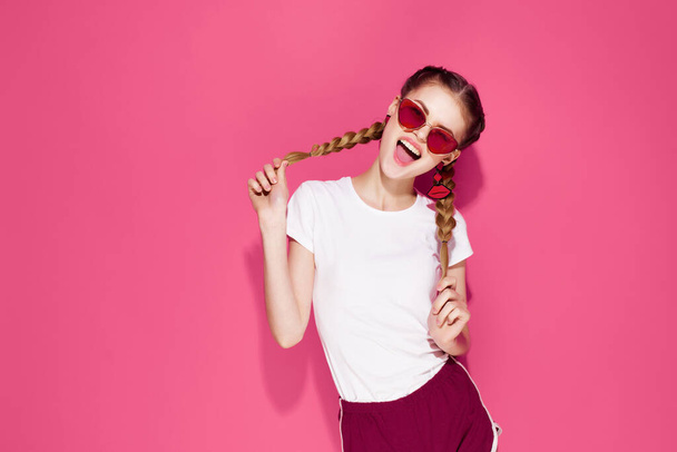 bonita mujer sosteniendo coletas verano moda ropa posando rosa fondo - Foto, Imagen