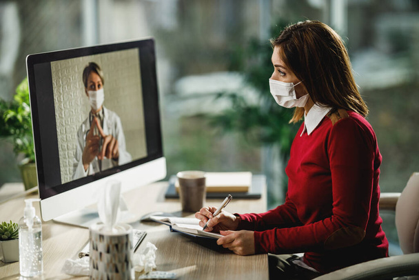 Egy fiatal női páciensről készült felvétel, aki jegyzeteket ír egy videohívás során egy orvosával egy számítógépen.. - Fotó, kép