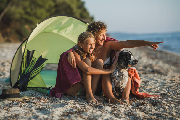 Joven mamá y su hija adolescente pasar el día en la playa con su lindo perro Cocker Spaniel.  - Foto, Imagen