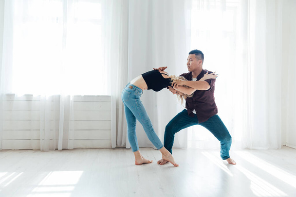 a man and a woman dance bachata to music in a white room - Photo, Image