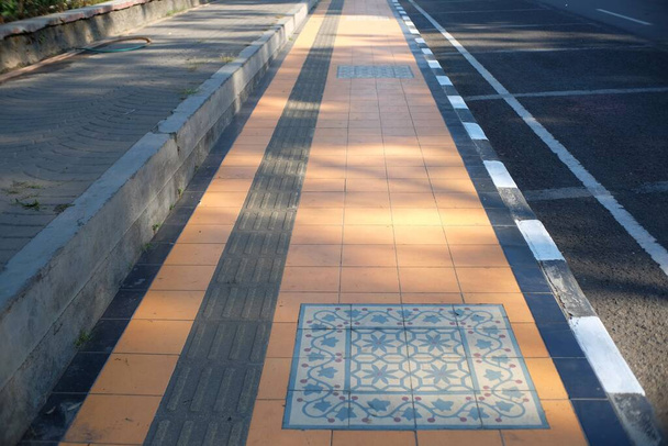 Pedestrian perspective with classic tiles on a paved roadside. - Foto, afbeelding
