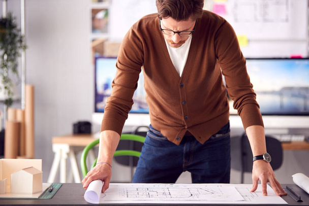 Male Architect In Office Unrolling Building Plan Or Blueprint On Desk - Foto, Imagem