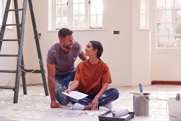 Couple Sitting On Floor With Paint Chart Ready To Decorate New Home - Фото, зображення