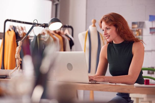 Female Student Or Business Owner Working In Fashion Using Laptop In Studio - 写真・画像