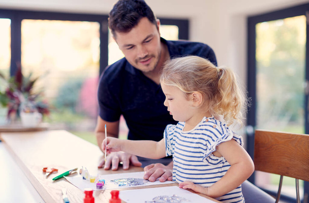 Father And Young Daughter Having Fun Doing Craft On Table At Home Together - Foto, Imagem