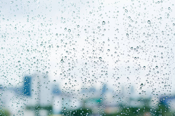 Sadepisara lasi-ikkuna päivällä monsuunikauden hämärtynyt kaupungin rakennusten tausta. - Valokuva, kuva