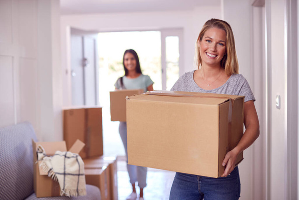 Portrait Of Female Couple Carrying Boxes Through Front Door Of New Home On Moving Day - Foto, Imagen