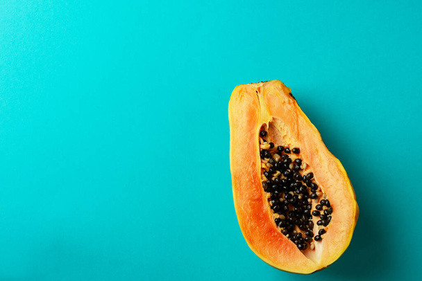 Summer composition. Tropical papaya fruits cut in half lie on a blue background. Summer concept. Flat lay, top view, copy space. - 写真・画像