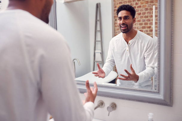 Man At Home Practising Giving Speech Or Presentation In Bathroom Mirror - Foto, Bild