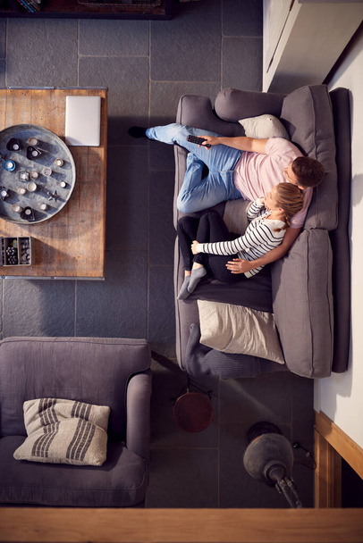 Overhead View Of Couple Relaxing On Lounge Sofa At Home And Watching TV Together - Foto, imagen