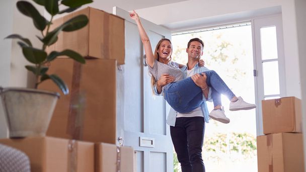 Man Carrying Woman Over Threshold Of New Home As Couple Move In Together - Fotoğraf, Görsel