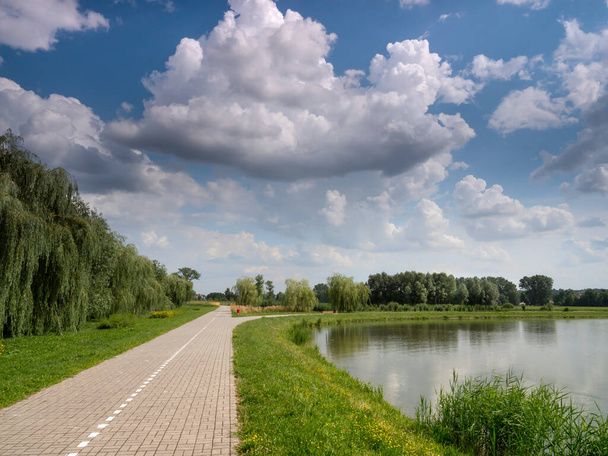 白い雲を背景に2つの湖の間を自転車道が走り - 写真・画像