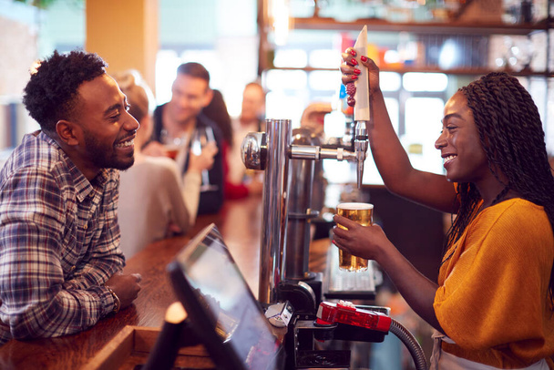 Smiling Female Bartender Behind Counter Serving Female Customer With Beer - Foto, Bild