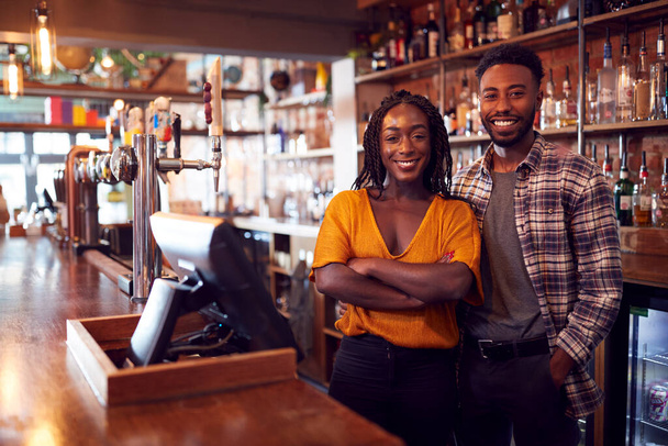 Portrait Of Smiling Couple Owning Bar Standing Behind Counter - Фото, изображение