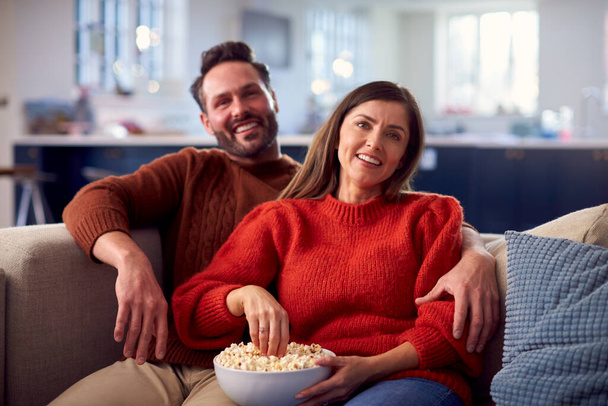 Couple Sitting On Sofa With Popcorn Watching TV Together - Foto, Imagen