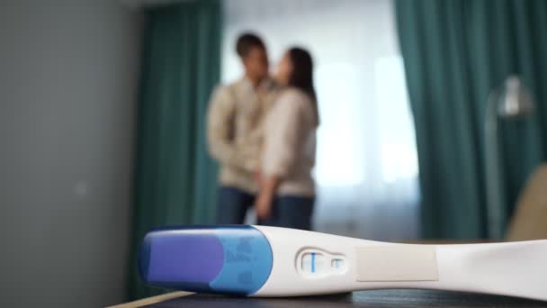 幸せなカップルを背景にした正の妊娠検査のクローズアップ - 映像、動画