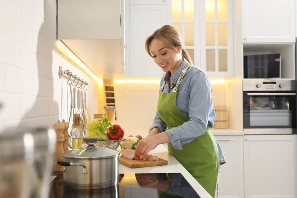 Woman cutting chicken meat to make bouillon in kitchen. Homemade recipe - Fotó, kép