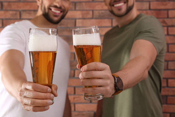 Barátok poharakkal sör közelében piros téglafal, közelkép - Fotó, kép