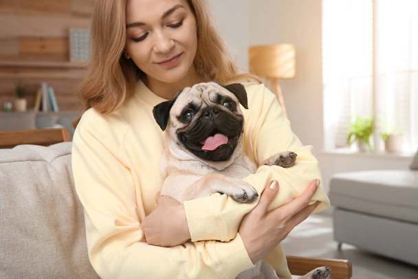 Woman with cute pug dog at home. Animal adoption - Фото, зображення