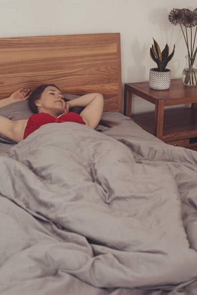 Young adult girl hiding in bed under blanket - Fotó, kép