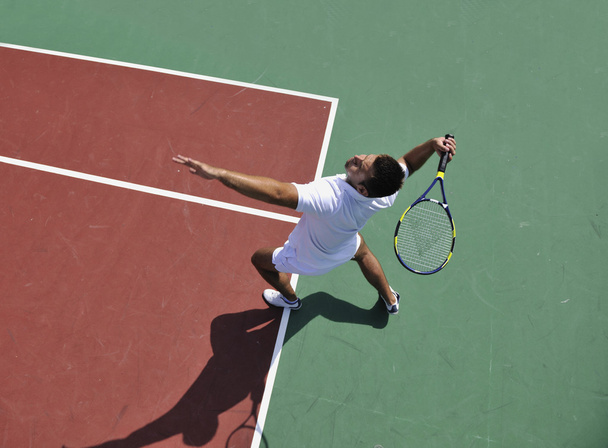 Young man play tennis outdoor on orange tennis court at early morning - Photo, image
