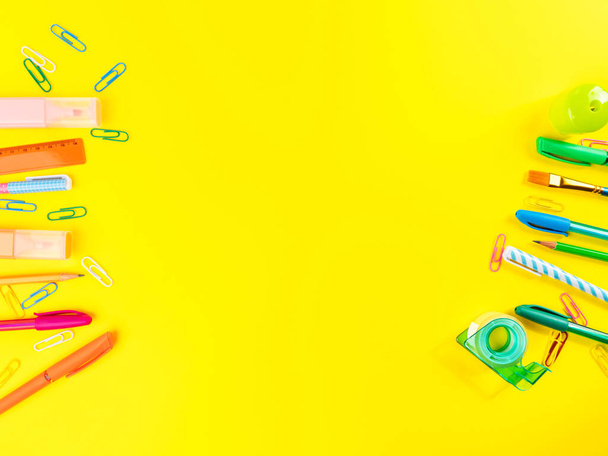 Back to school concept. Colorful writing tools frame on yellow background - Foto, afbeelding