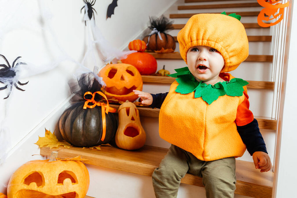 Cute smiling baby dressed as pumpkin looking at camera - Foto, afbeelding