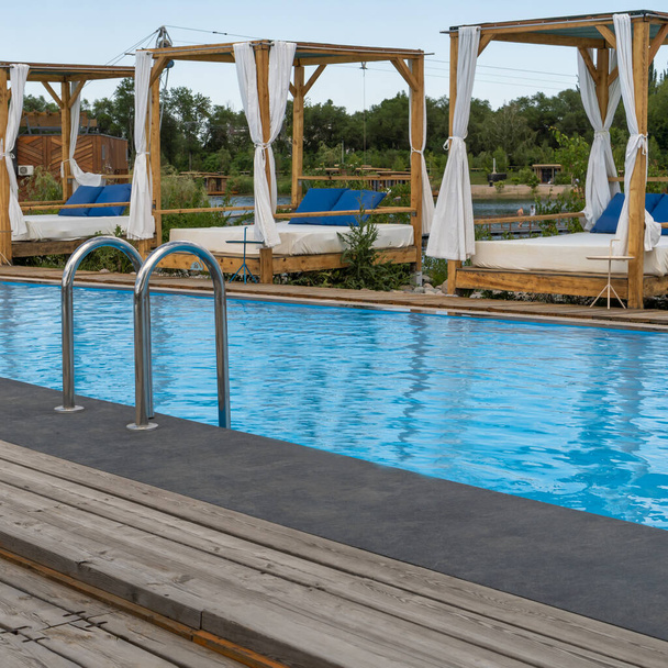 Une piscine étroite avec de l'eau bleue claire sur le fond des chaises longues extérieures - Photo, image