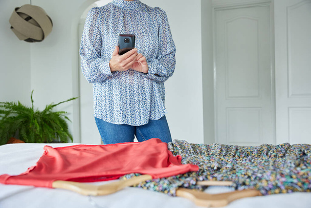 Close Up Of Woman Photographing Unwanted Clothes With Mobile Phone To Sell Online - Foto, immagini