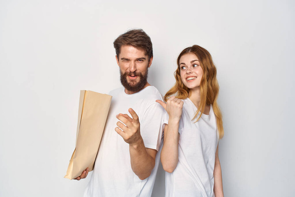 young couple in white t-shirts paper bag shopping - Foto, imagen