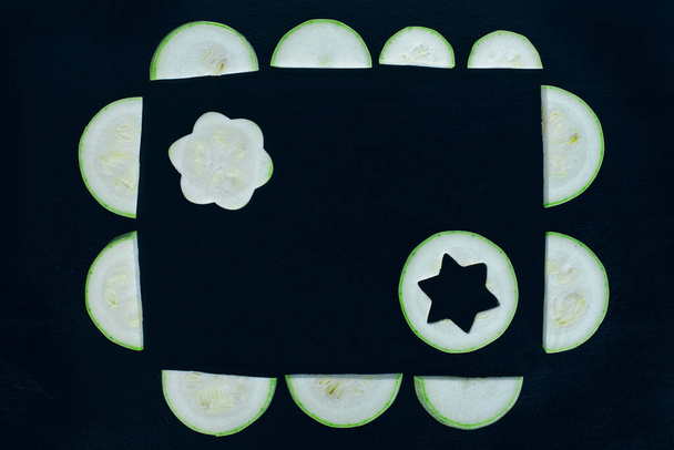 Una cornice di fette di zucchine a mezzaluna con due fette tagliate creativamente all'interno. Legumi da zucca estivi. - Foto, immagini