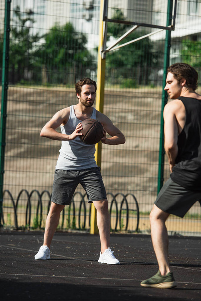 Man holding basketball ball near blurred friend on playground  - Foto, Bild