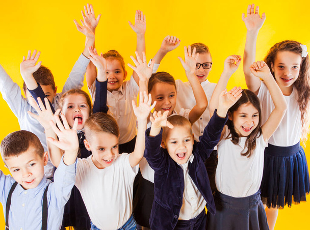 The happy schoolchildren in uniform raised their hands up - 写真・画像