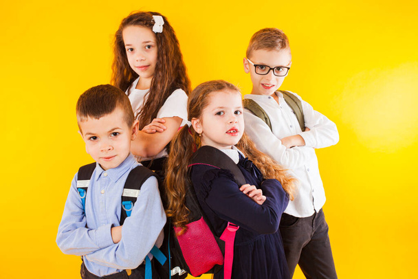 The smart and serious pupils are standing with folded arms - Фото, изображение